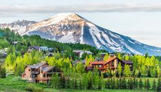 the mountains are covered in snow and green trees, while houses sit on the hillside