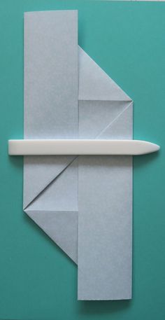 an origami piece with a pencil sticking out of it on a blue background