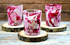 three pink and white marbled glass votives sitting on wood slices, with one candle holder in the middle