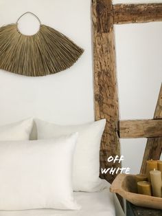 a bed with white sheets and pillows in front of a wooden wall hanging over it