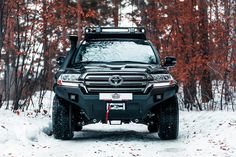 the front end of a black four - doored suv driving through snow covered trees