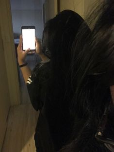 a woman taking a selfie with her cell phone in front of her face and dark hair