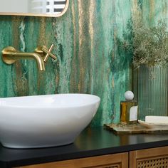 a white bowl sink sitting on top of a wooden counter next to a green wall