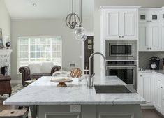 a large kitchen with white cabinets and marble counter tops, along with an island in the middle