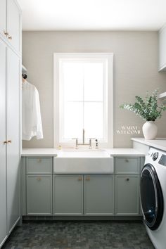 a washer and dryer in a small room next to a window with a potted plant