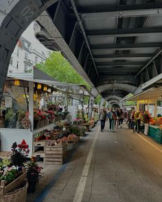 an outdoor market with people shopping and selling flowers