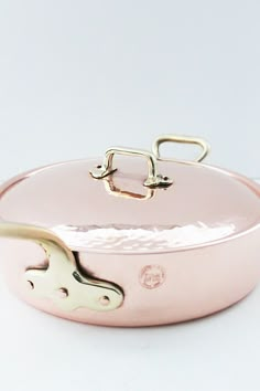 a pink pan with gold handles on a white surface