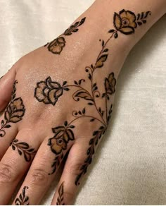 a woman's hand with hennap and flowers painted on it, sitting on top of a bed