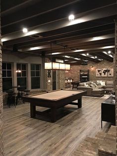 a pool table in the middle of a living room with couches and tables around it