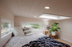 a bed in a room with white walls and wood flooring next to a window