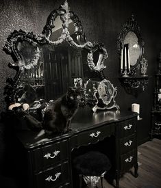 a black and white photo of a cat sitting on top of a dresser in front of a mirror