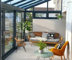 a living room filled with furniture and lots of glass doors on the wall to let in light