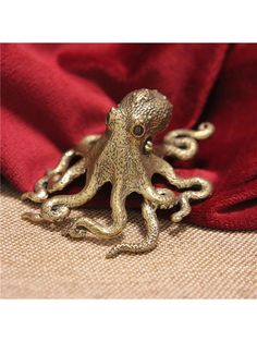 an octopus figurine sitting on top of a red cloth next to a gold chain