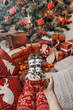 a person laying in front of a christmas tree with presents on the floor next to it