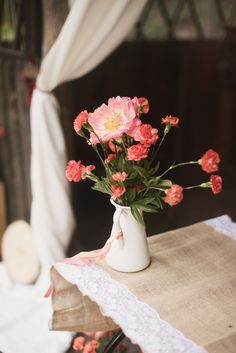 pink flowers are in a white vase on a table