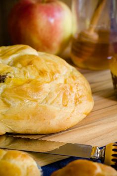 a pastry sitting on top of a cutting board next to an apple and honey jar