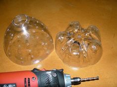 an electric drill is laying next to a clear glass bowl on a wooden table with holes in it