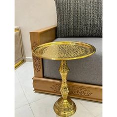 a golden tray sitting on top of a wooden table next to a gray couch and chair