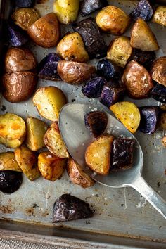 a pan filled with cooked potatoes and other vegetables next to a spoon on a table