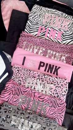 pink and black clothes are stacked on top of each other in a suitcase with zebra print