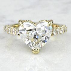 a heart - shaped diamond ring with two rows of diamonds on the band, set in 18k yellow gold