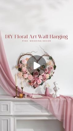 a white fireplace with pink flowers on it and a heart hanging from the mantel