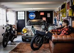 a man sitting on a leather chair in a garage next to a motorcycle and car