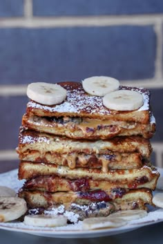 a stack of french toast with bananas and powdered sugar on top, sitting on a plate