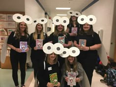 a group of women standing next to each other holding up some paper circles with faces on them