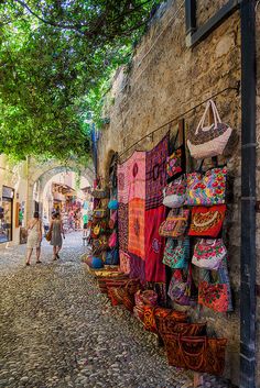 people walking down an alley way with baskets and bags on the wall in front of them