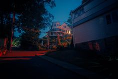 a house is lit up at night with red lights on the street and trees around it