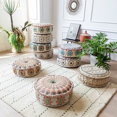 several decorative round ottomans on a rug in front of a potted plant and mirror