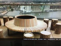 a wooden bench sitting on top of a balcony next to tall buildings and water in the background