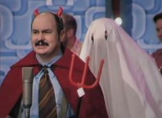 a man dressed as a ghost and holding a microphone in front of two other men