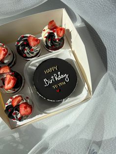 a box filled with cupcakes covered in frosting and topped with strawberries