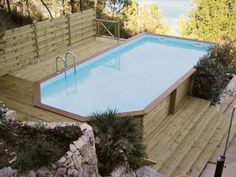 an above ground swimming pool surrounded by rocks and wood fenced in area with stairs leading up to it