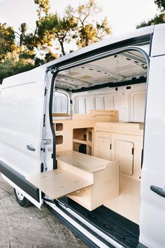 the interior of a white van with its doors open and wooden shelves in the back