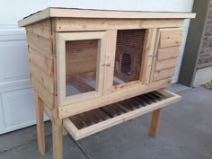 a wooden chicken coop with two doors and one door open on the side of the house