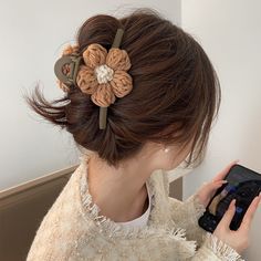 a woman is looking at her cell phone while wearing a flower hair clip in her hair