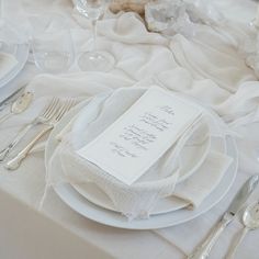 the table is set with silverware and white linens for an elegant wedding reception