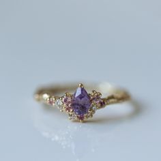 a close up of a ring on a white surface with a purple stone in the middle