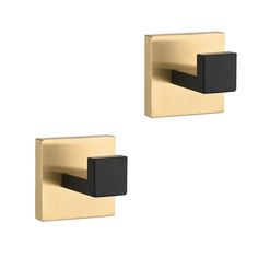 two black and gold square hooks on a white wall