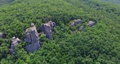 an aerial view of some rocks in the middle of a green forest with lots of trees