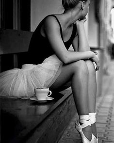 a black and white photo of a woman sitting on a bench with her legs crossed