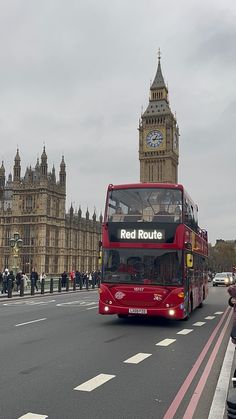 a red double decker bus driving down the street in london, england with big ben in the background