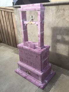 a purple box sitting on top of a sidewalk next to a wall with writing on it