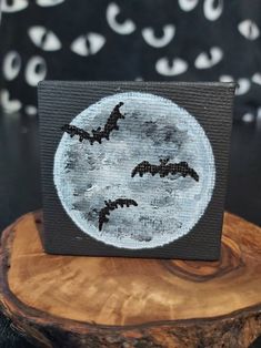 a painting on top of a piece of wood with bats flying over the full moon