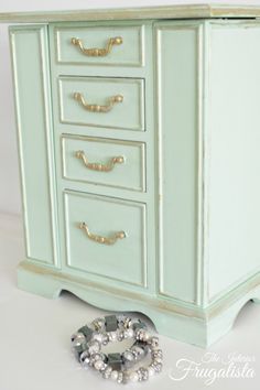 an old dresser with drawers and some beads on the floor next to it is painted mint green