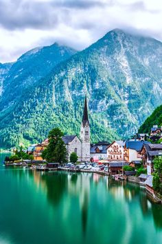 a lake surrounded by mountains and houses in the foreground with a church on top