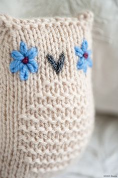 a knitted pillow with blue flowers on it